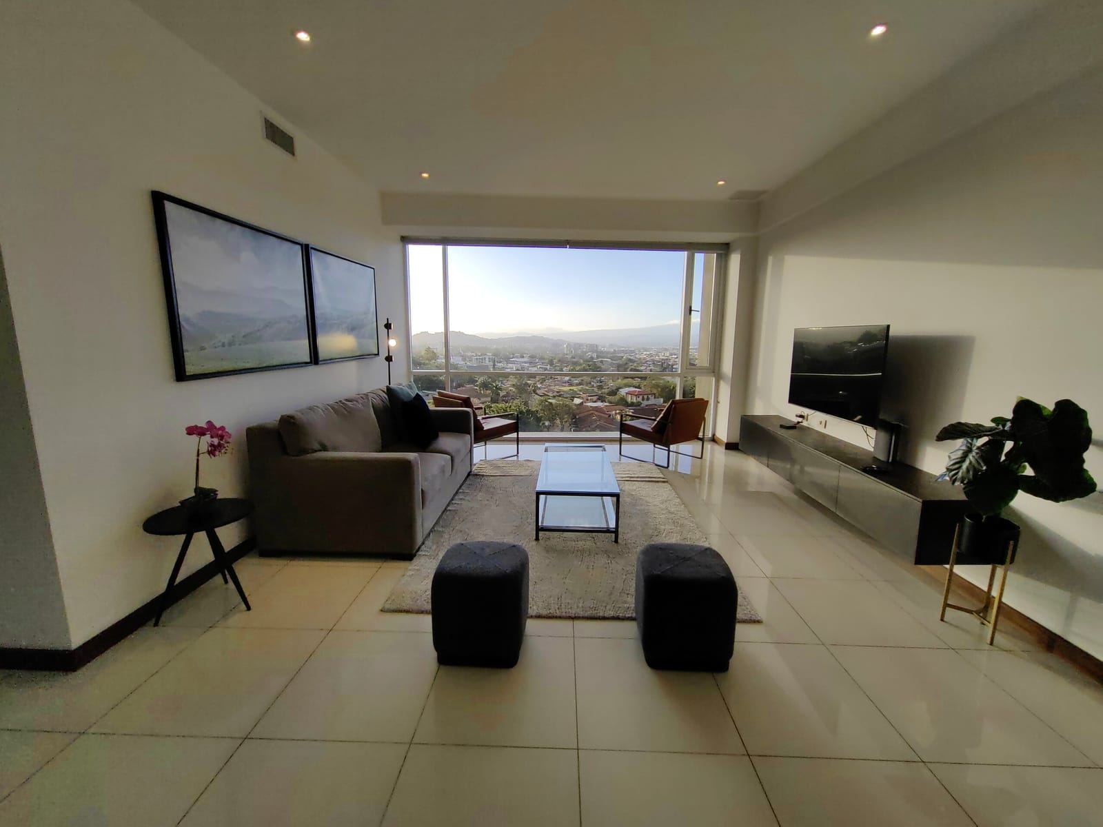 Living room with sofa, poufs and window at dusk