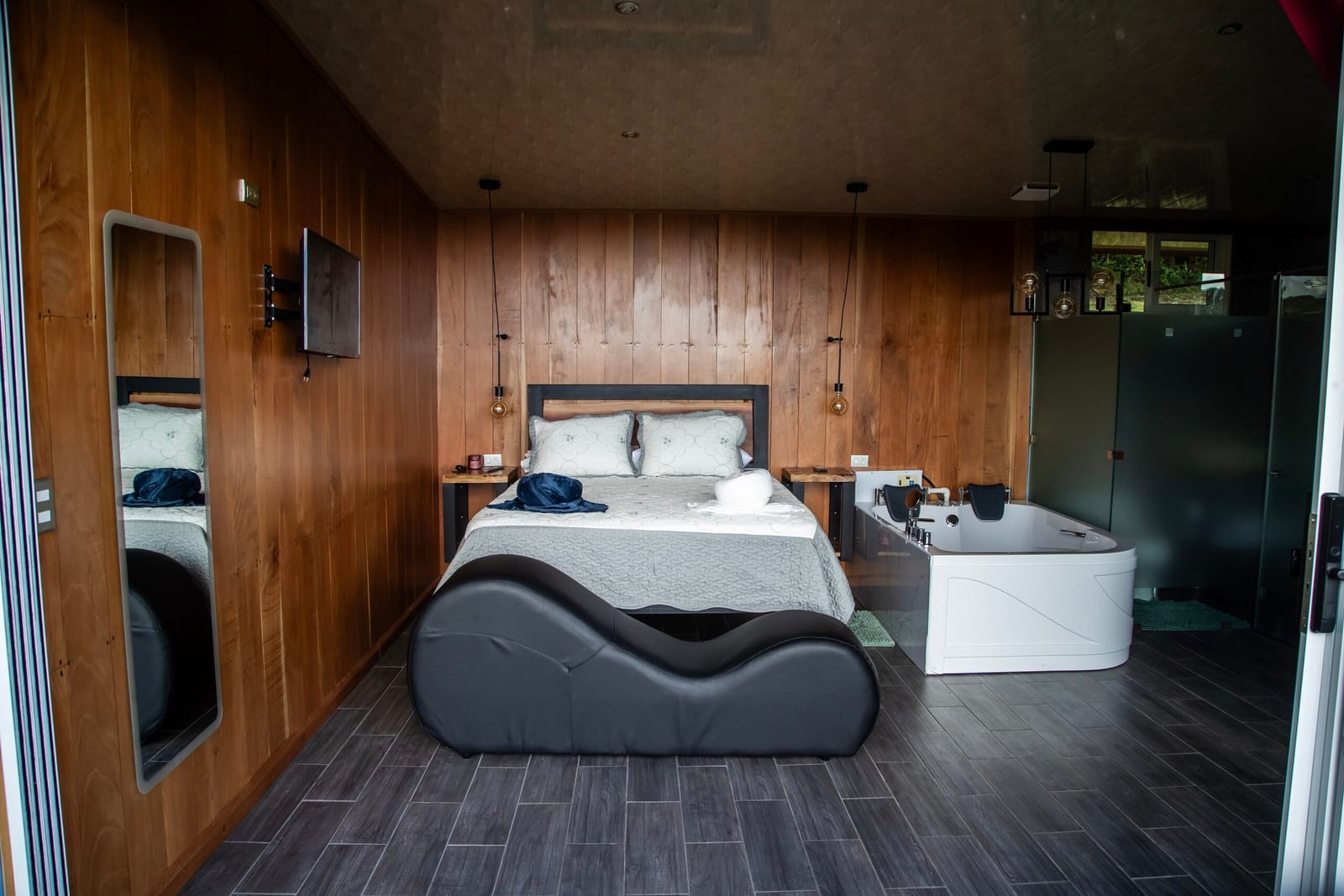 Queen bed and two-person jacuzzi behind frosted glass