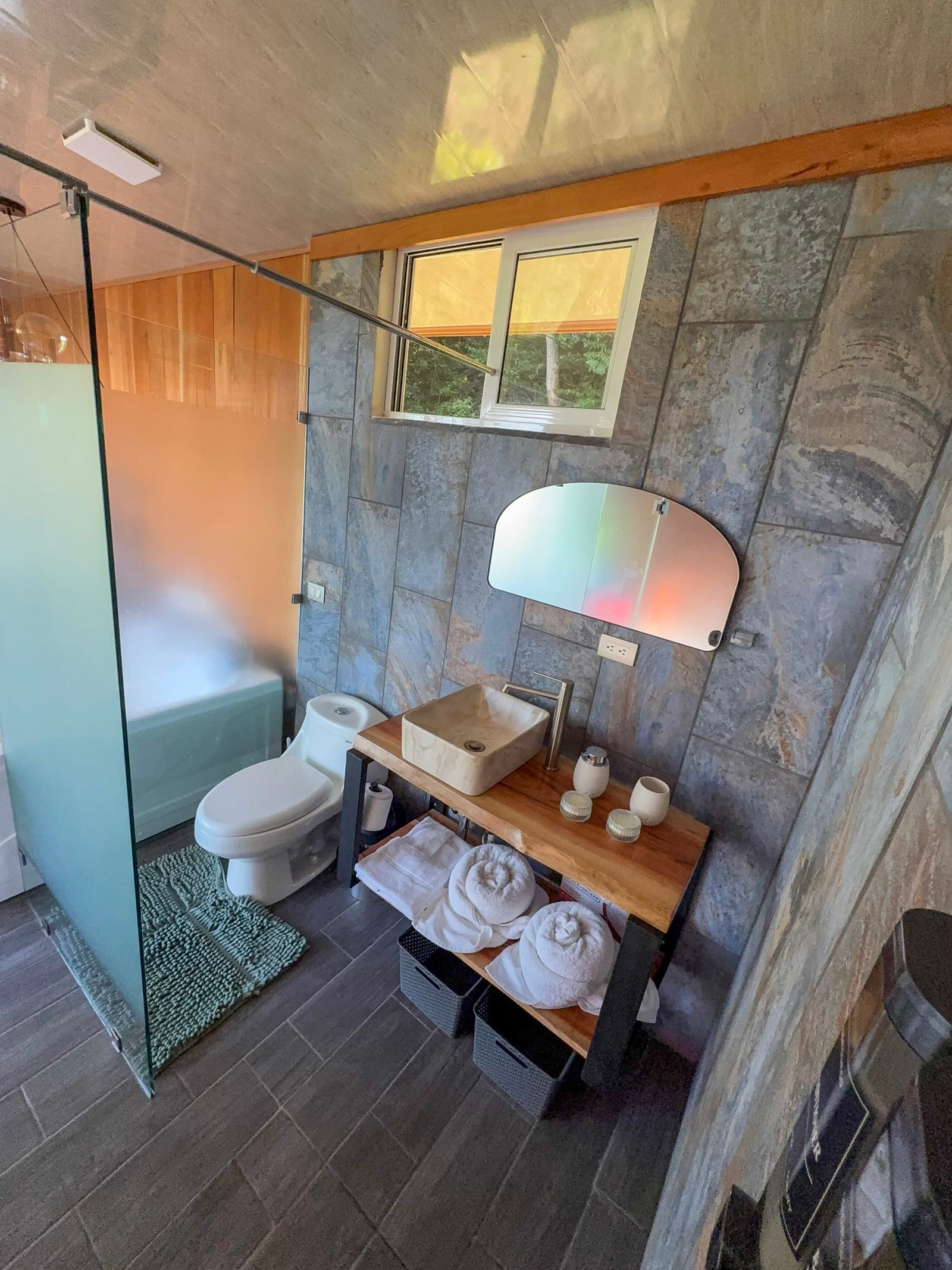 Bathroom vanity with round mirror, towels and window