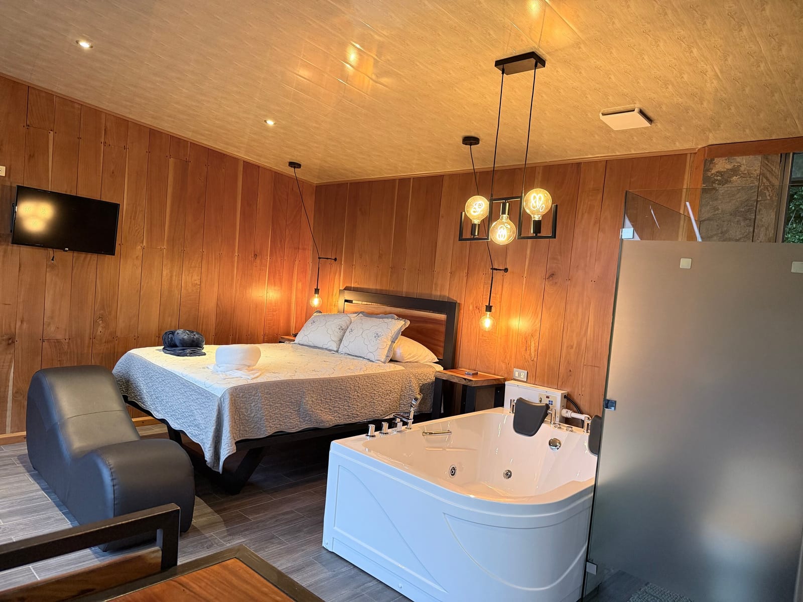 Bedroom with jacuzzi, TV and pendant lights at dusk