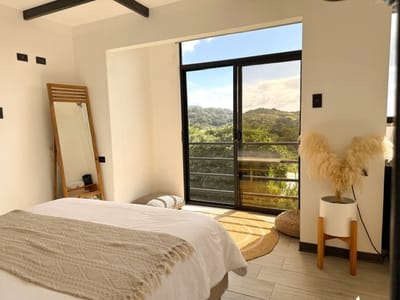 Queen bed facing the glass door to the balcony and forest