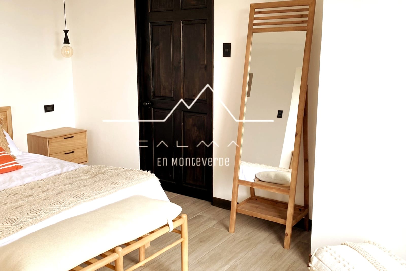 Full-height mirror beside the bed and Calma logo
