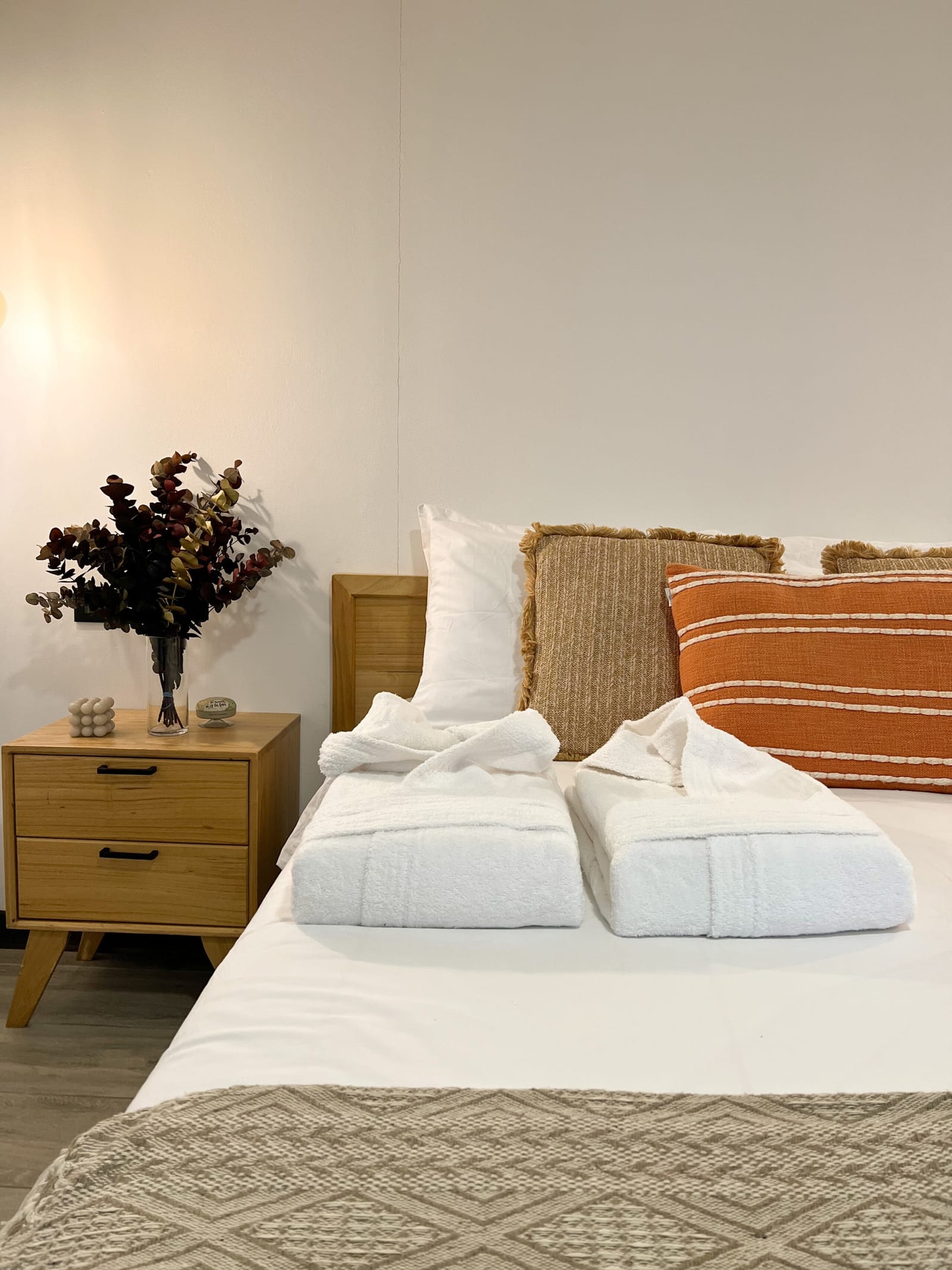 Bedside drawers with dried flowers beside the bed