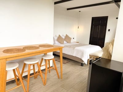 High wooden table with three stools beside the bed