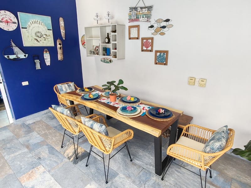 Wooden dining table with rattan chairs and nautical wall decor