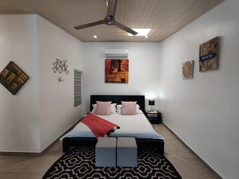 King bedroom with dark headboard, red throw and patterned rug