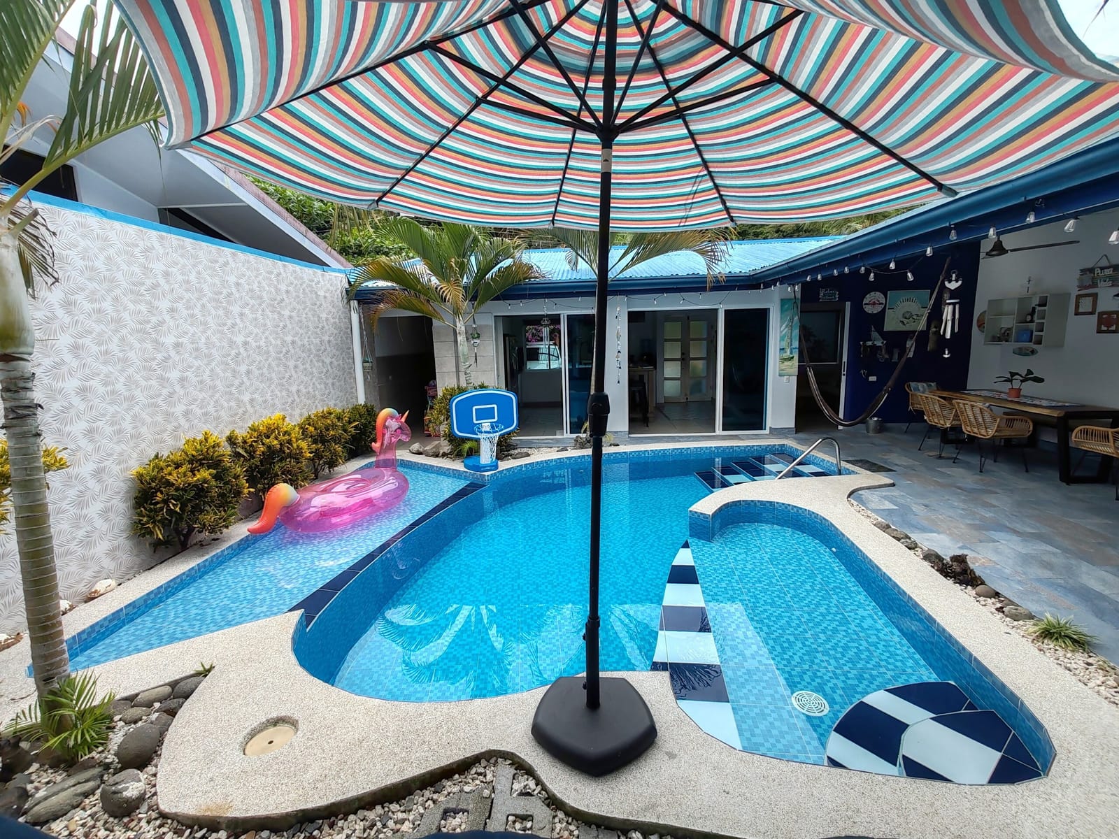 Pool with a pink flamingo float under a striped umbrella