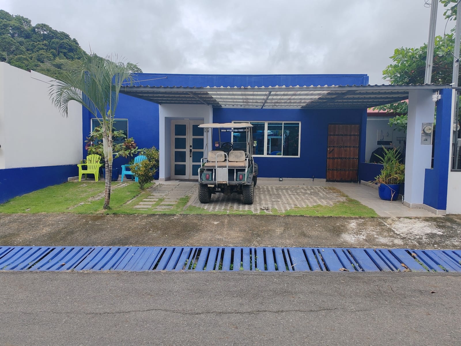 Blue house front with golf cart parked under the carport