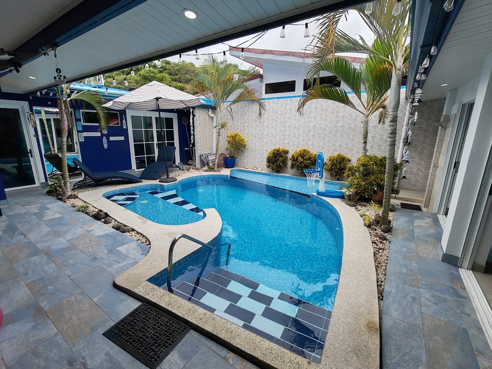 Pool seen from the covered terrace with palms