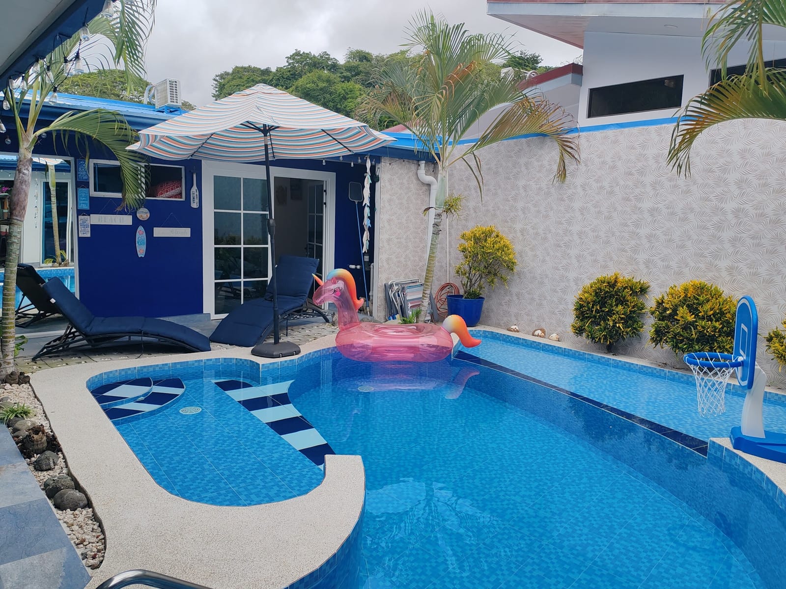 Pool and flamingo float with palms and umbrella