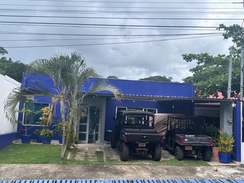 Two Can-Am Mule off-road vehicles parked in front of the blue house