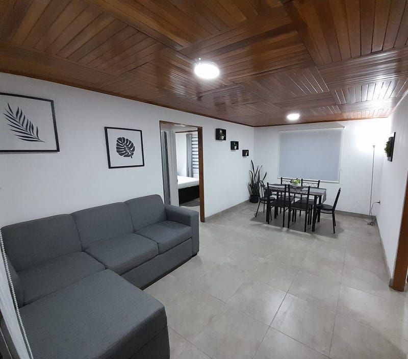 Living room with gray sectional sofa and dining table under wood ceiling