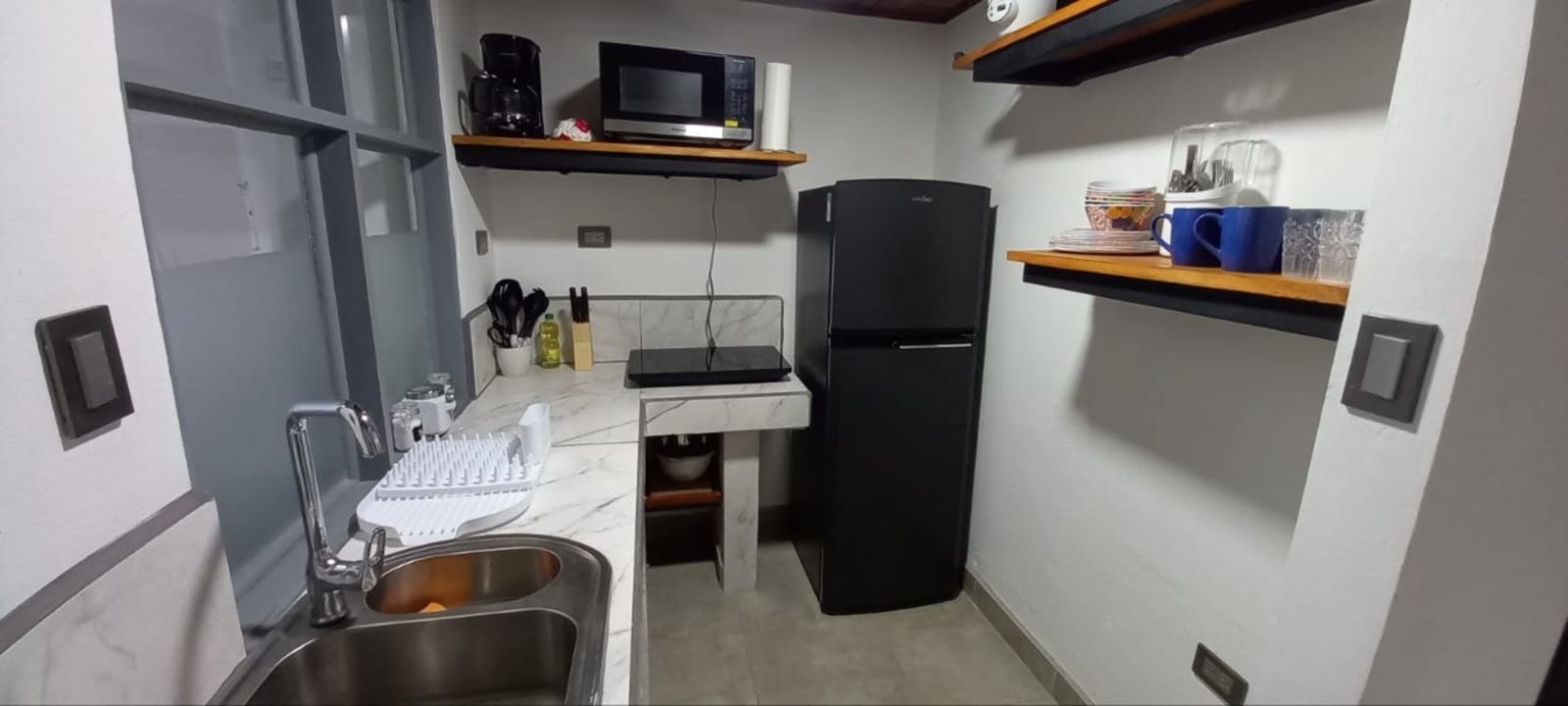 Kitchen with sink, microwave, coffee maker and open shelf