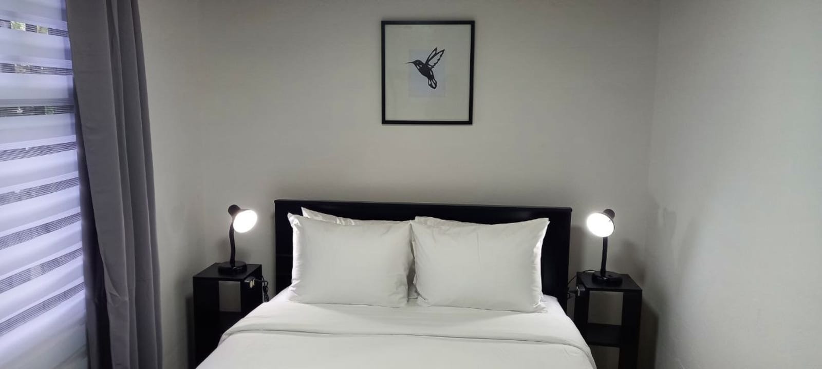 Bedroom with two bedside lamps and a hummingbird print