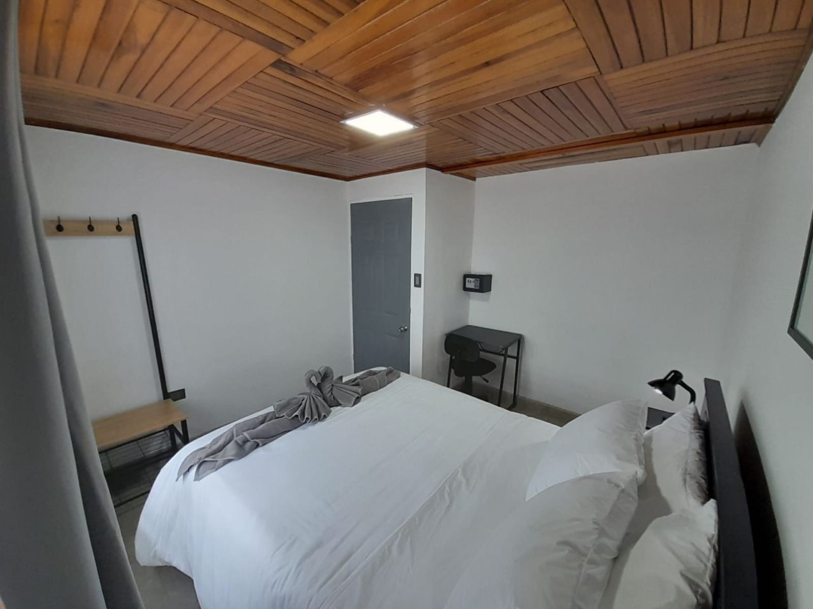 Bedroom with a coat rack, bench and wood ceiling