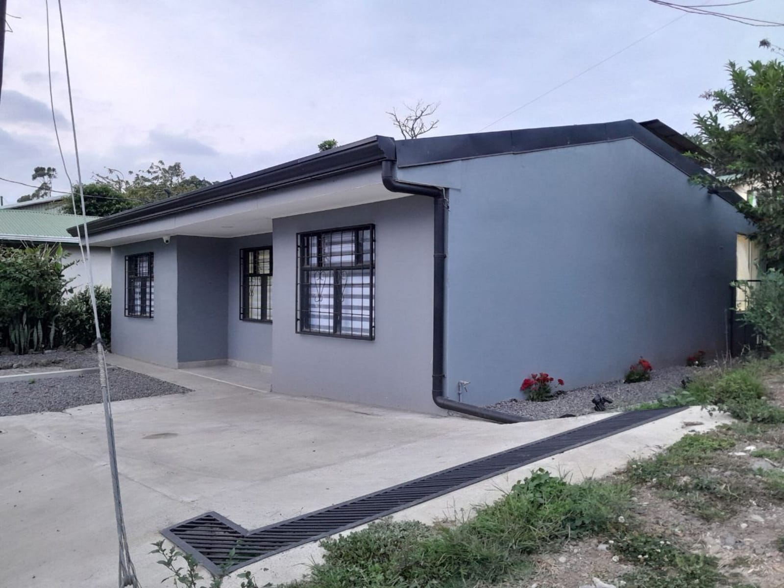 Side of the gray house with a garden strip and gravel