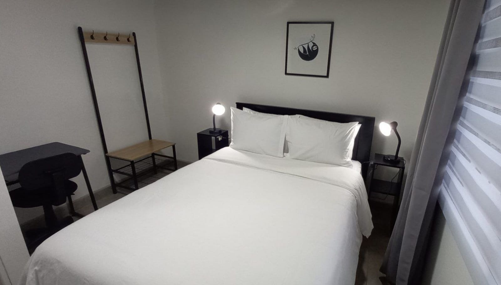 Bedroom with desk, coat rack and roller blind