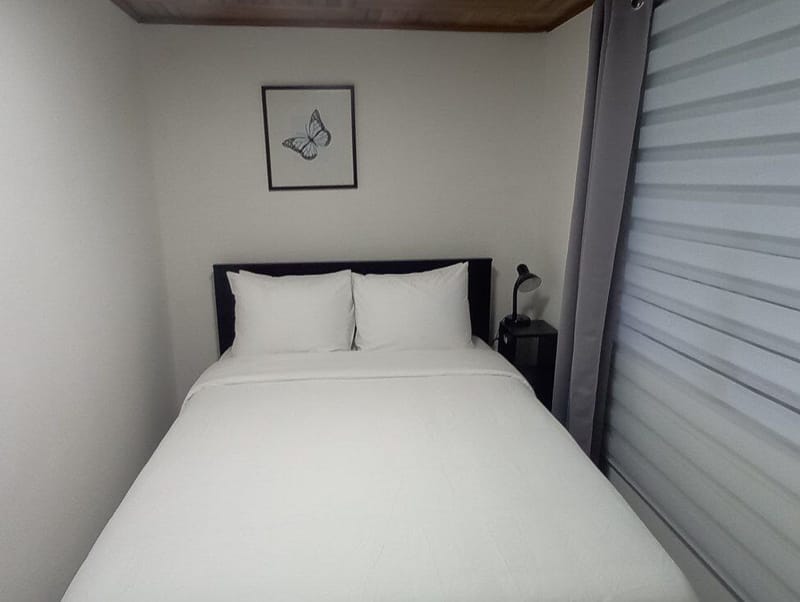 Bed with two pillows beside a striped blind