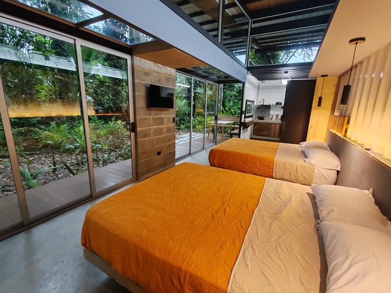 Two queen beds with orange covers opening to the glass wall
