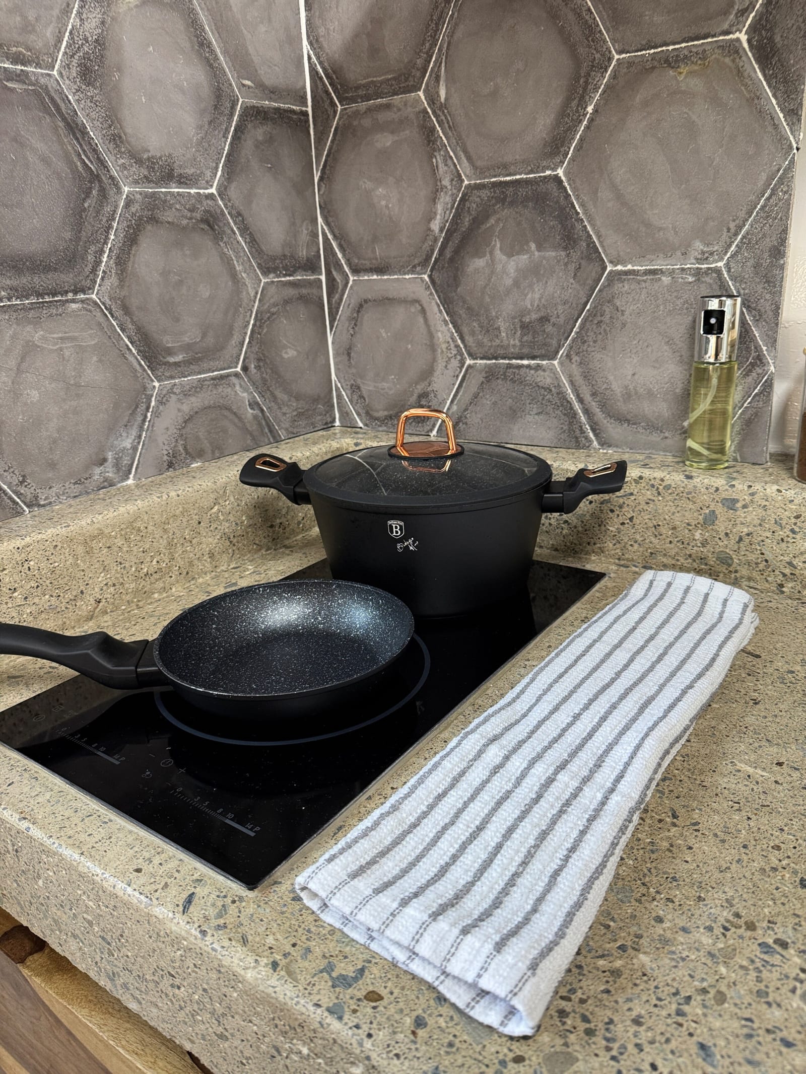 Black pans on the cooktop against hexagon tiles