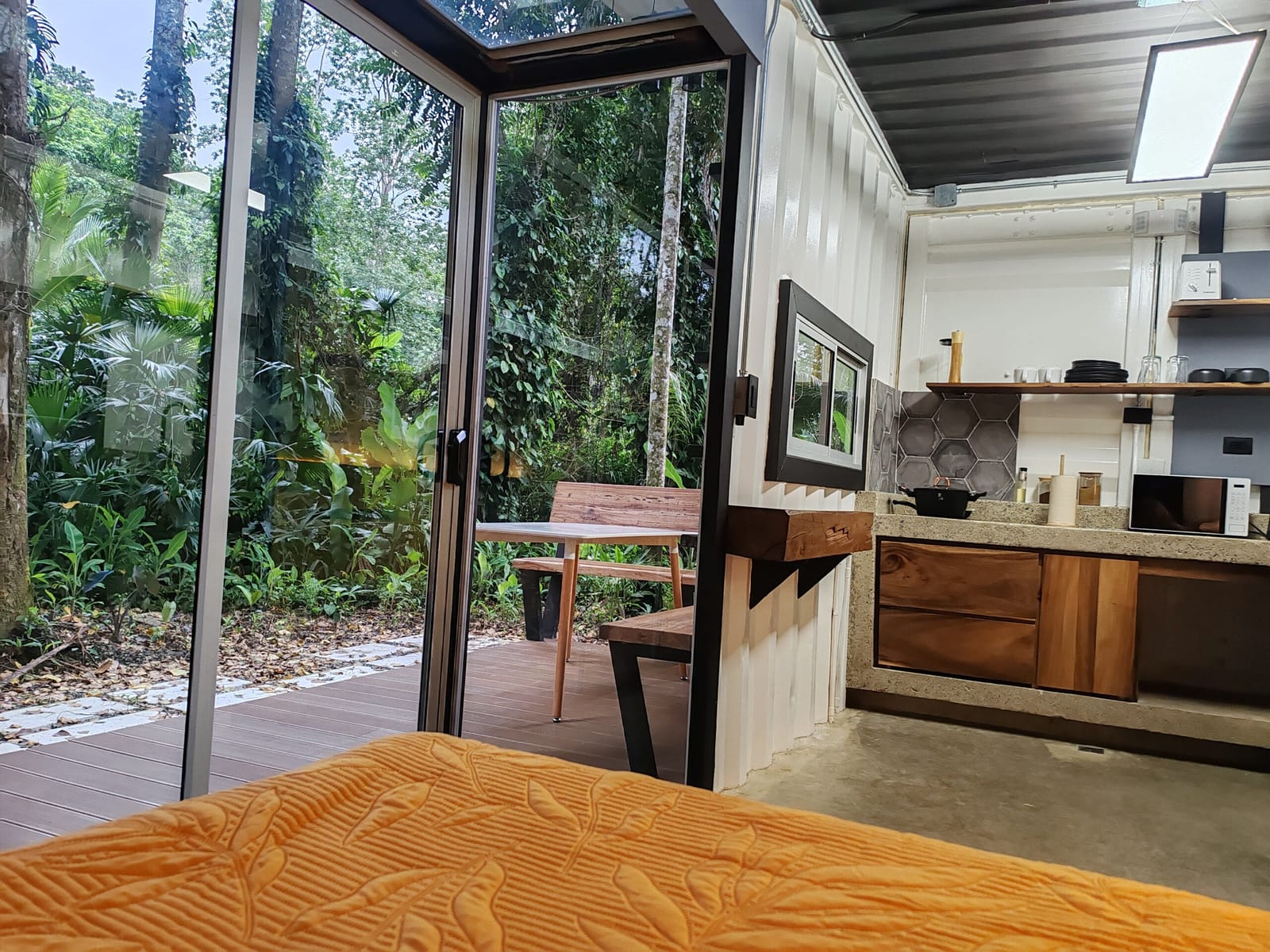 Open glass wall from the bed toward the kitchenette
