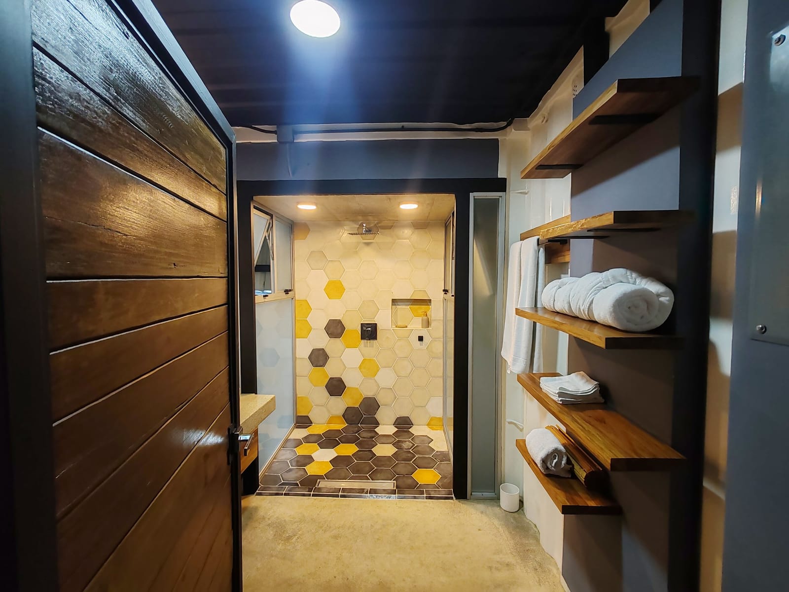 Wooden door open to the shower and towel shelves