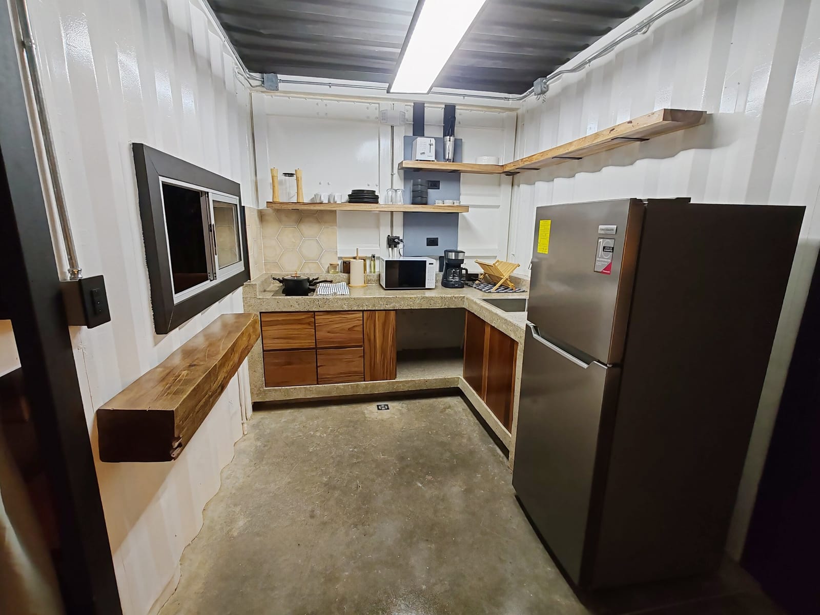 Kitchenette with stainless refrigerator, wood drawers and open shelves