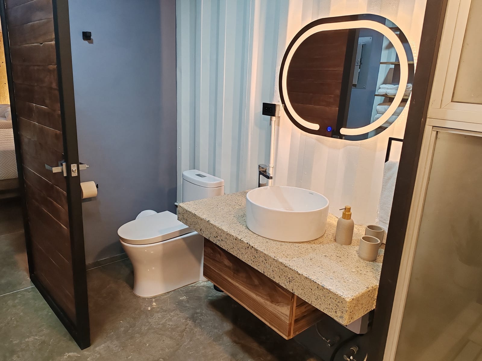 Round backlit mirror over the vessel sink and toilet