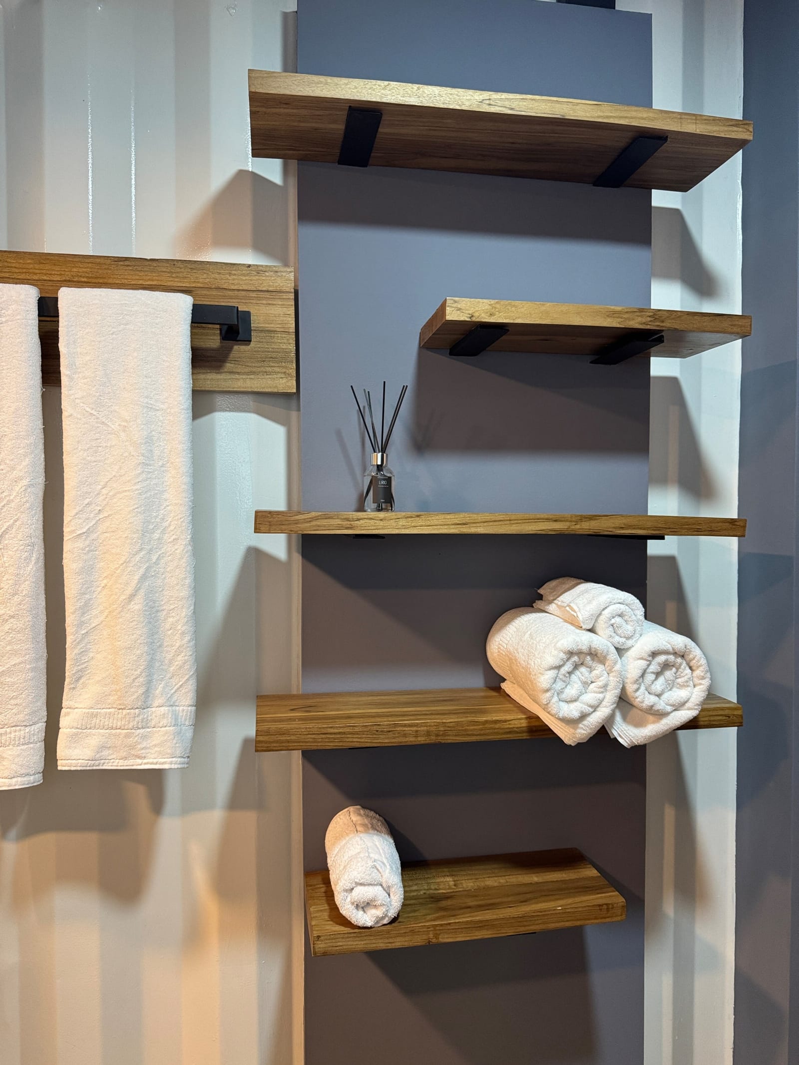 Rolled towels on wooden shelves on the gray bathroom wall