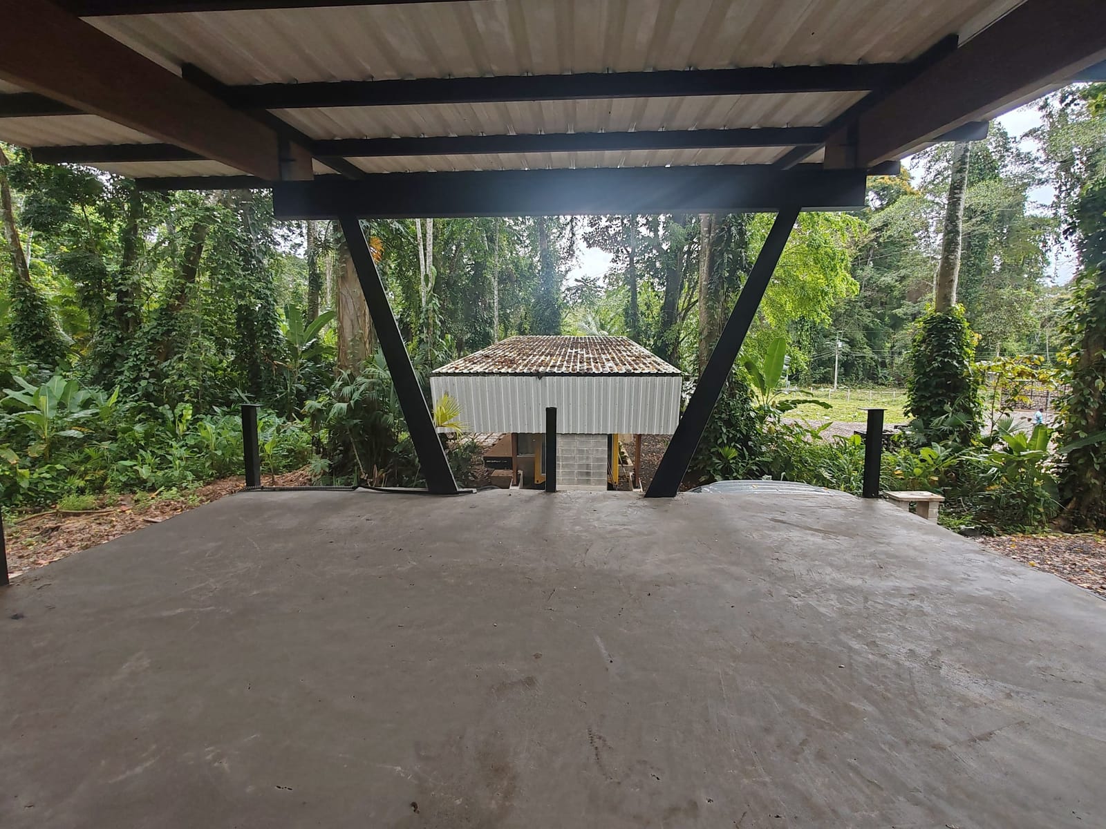 Covered parking canopy with gravel floor and trees