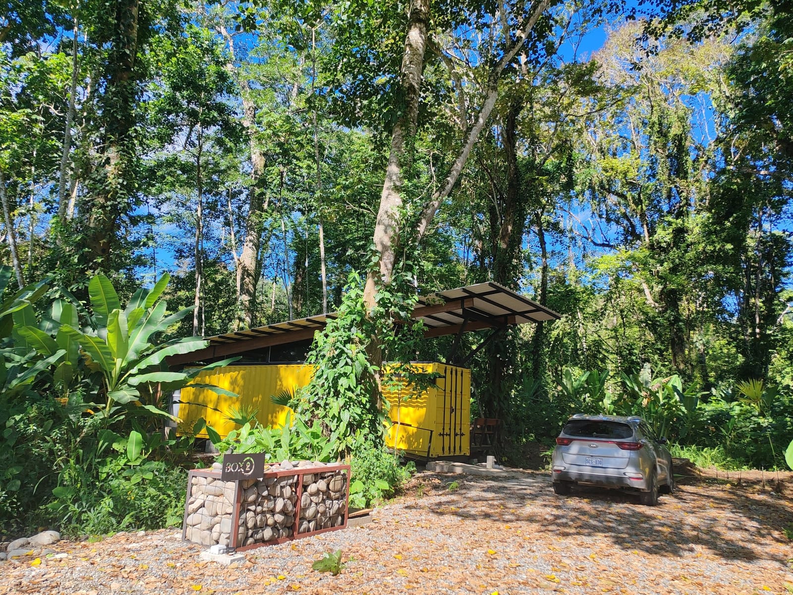 Yellow container and a parked car among the jungle trees