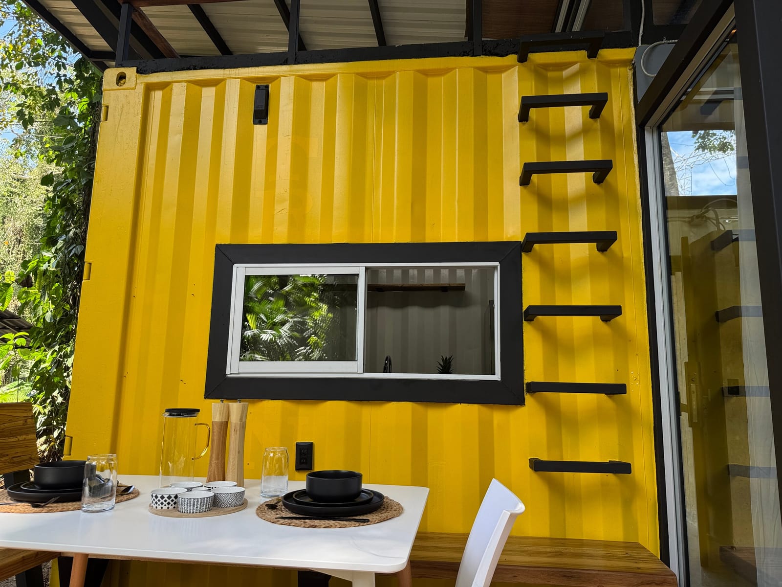 Yellow container wall with black window frame and ladder rungs