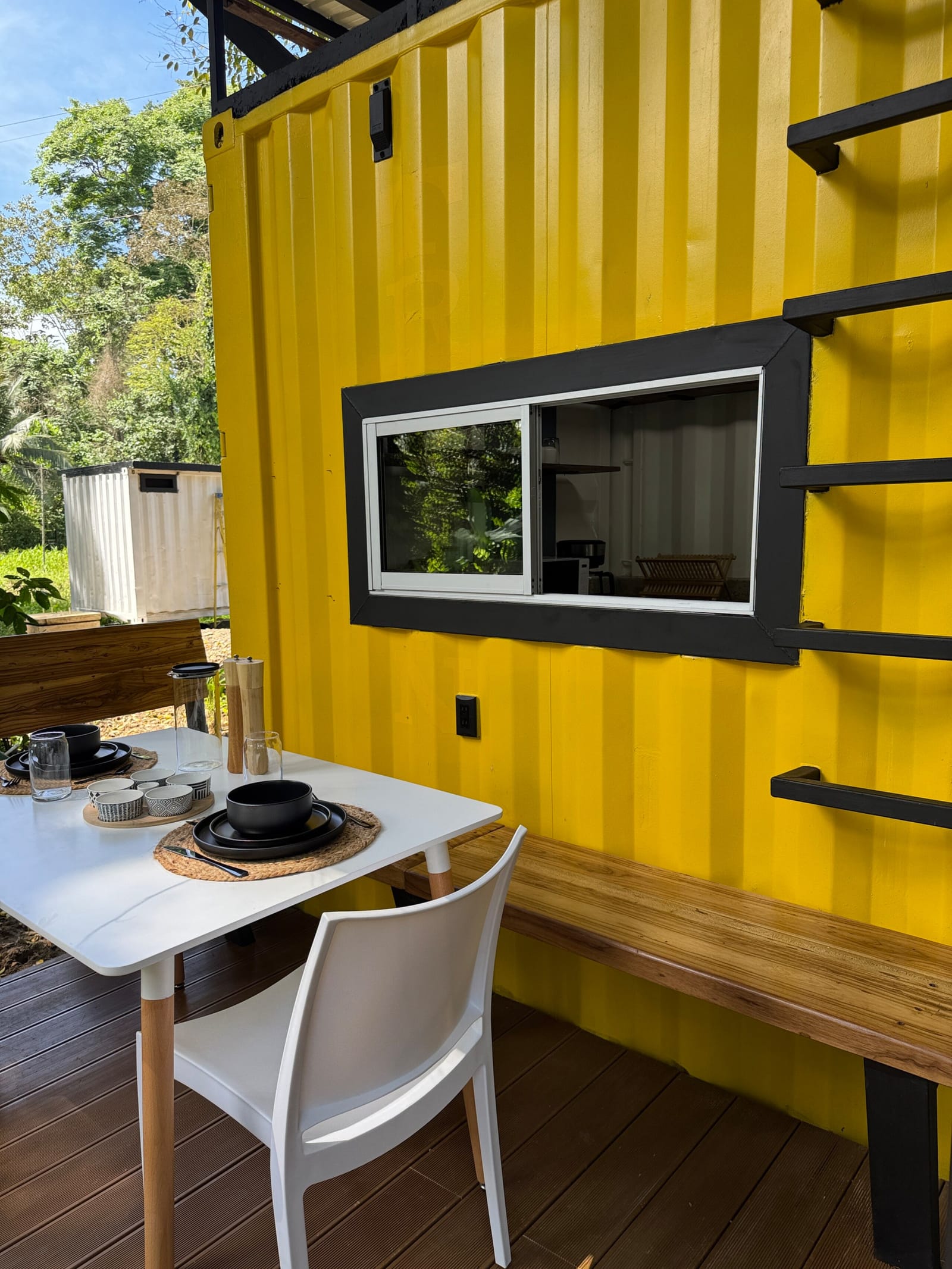 Deck table with two chairs against the yellow container