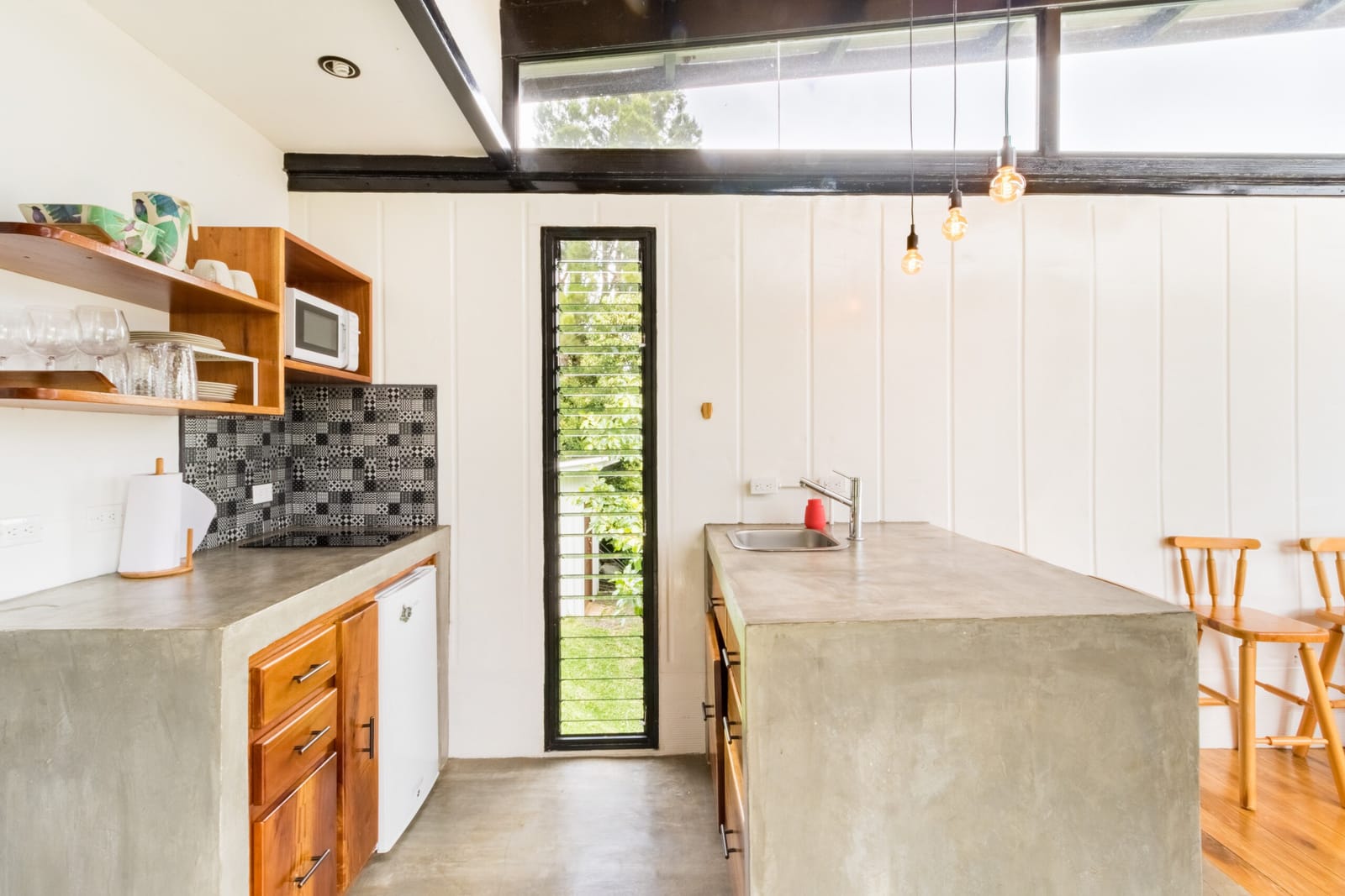 Full kitchen with stove, oven, open shelves and concrete counters