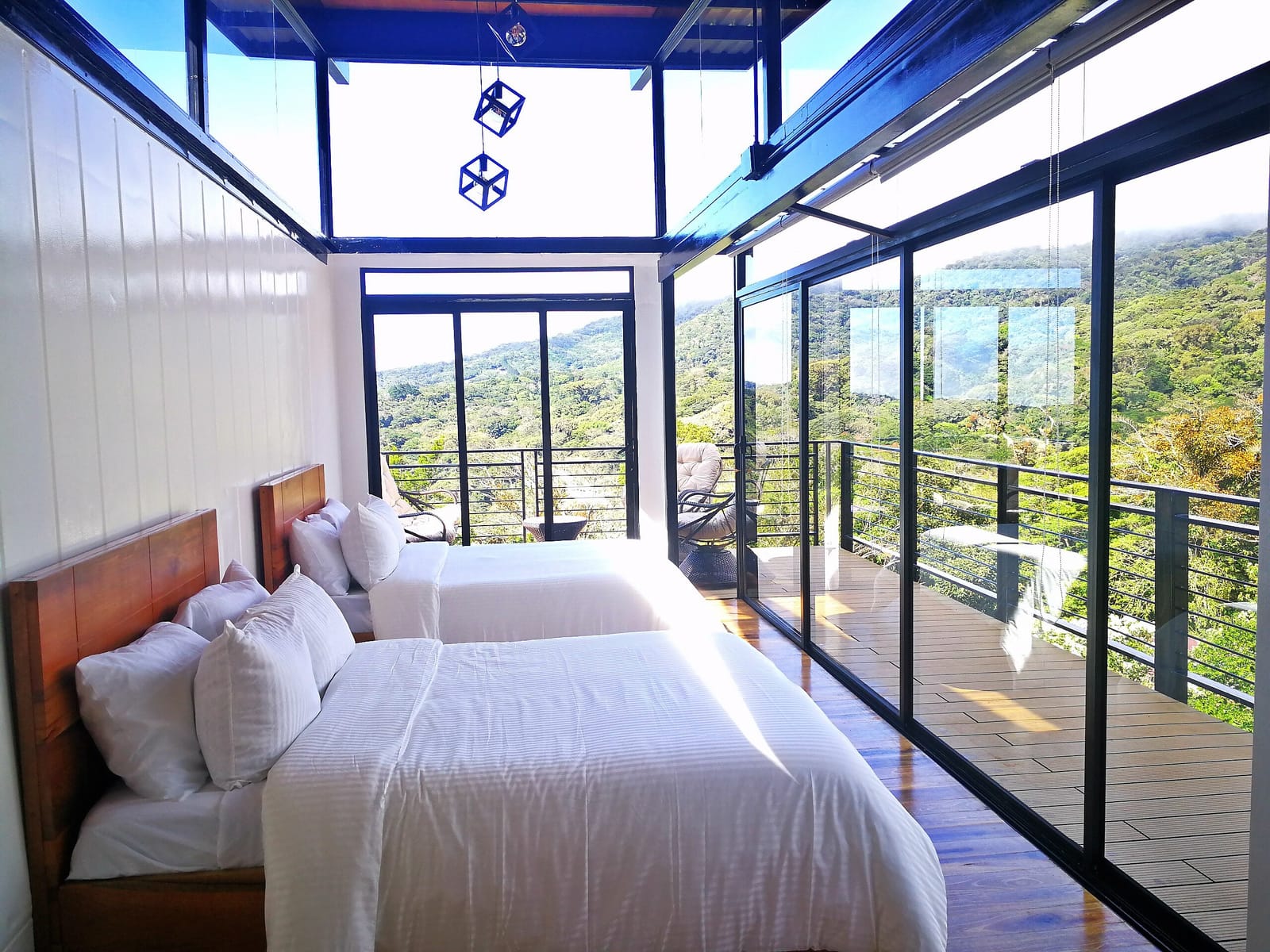 White bedding on two queen beds under the glass roof