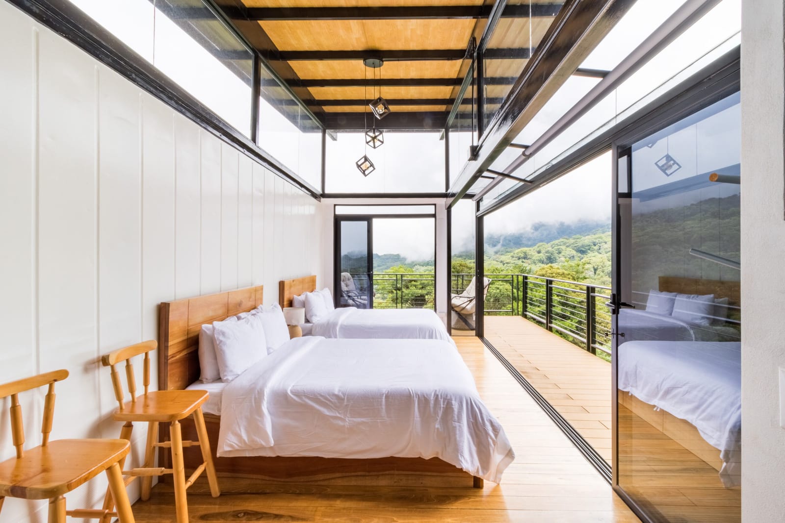 Queen beds beside the open glass door to the deck