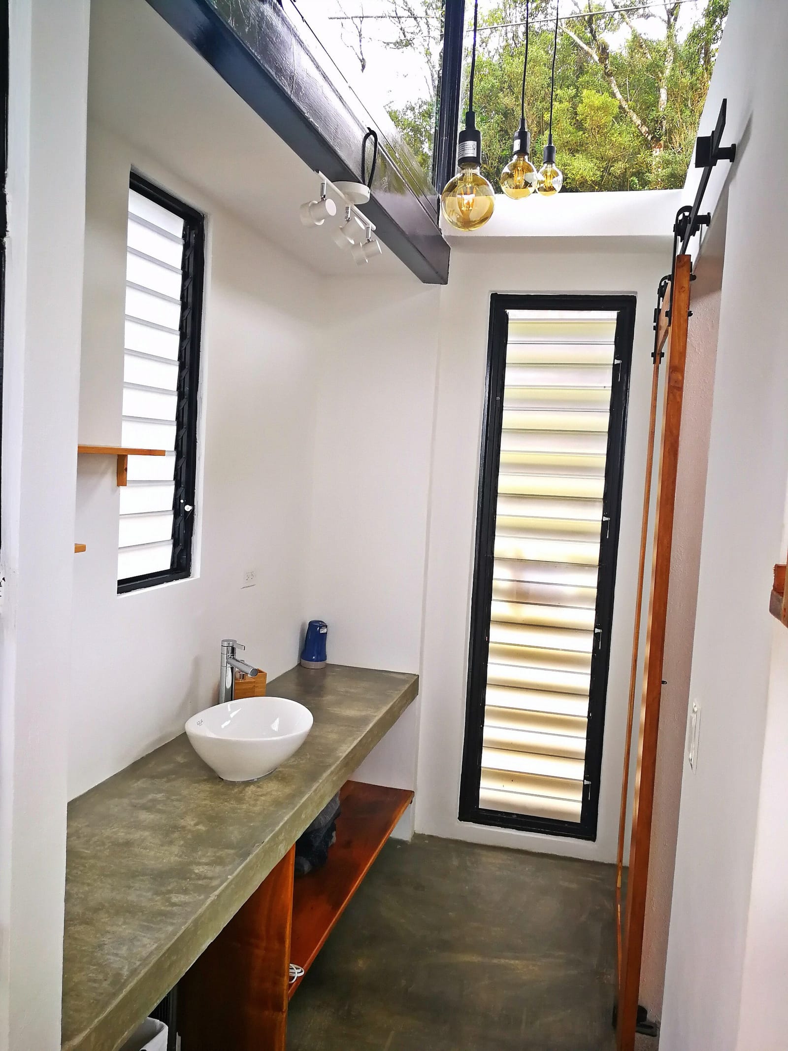 Vessel sink on a concrete counter outside the bathroom