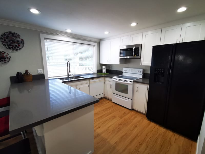 White kitchen with black refrigerator, electric range and microwave