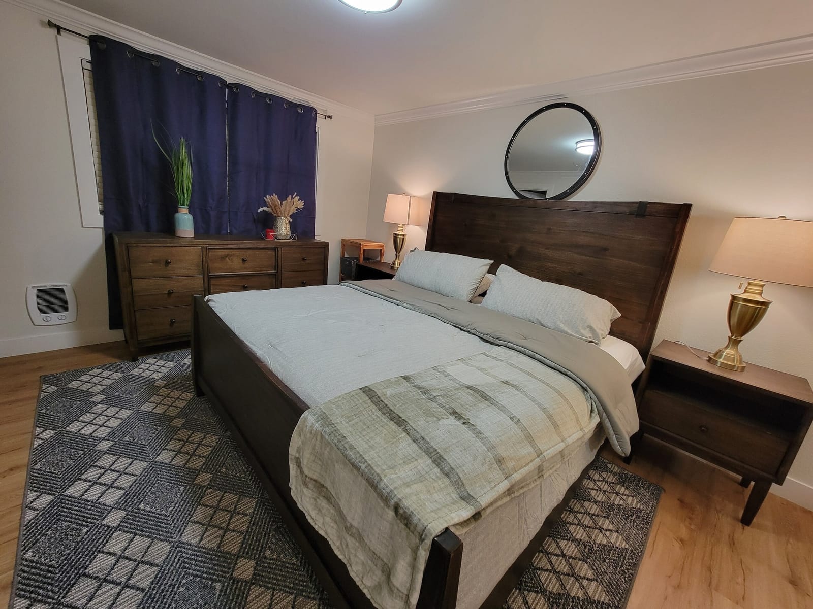 King bedroom with dresser, plant and patterned rug