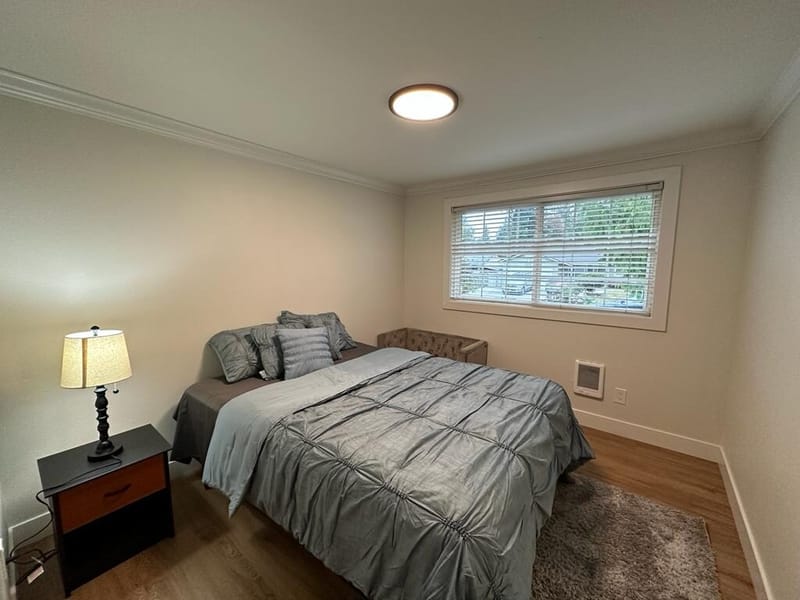 Second bedroom with window, lamp and gray bedding