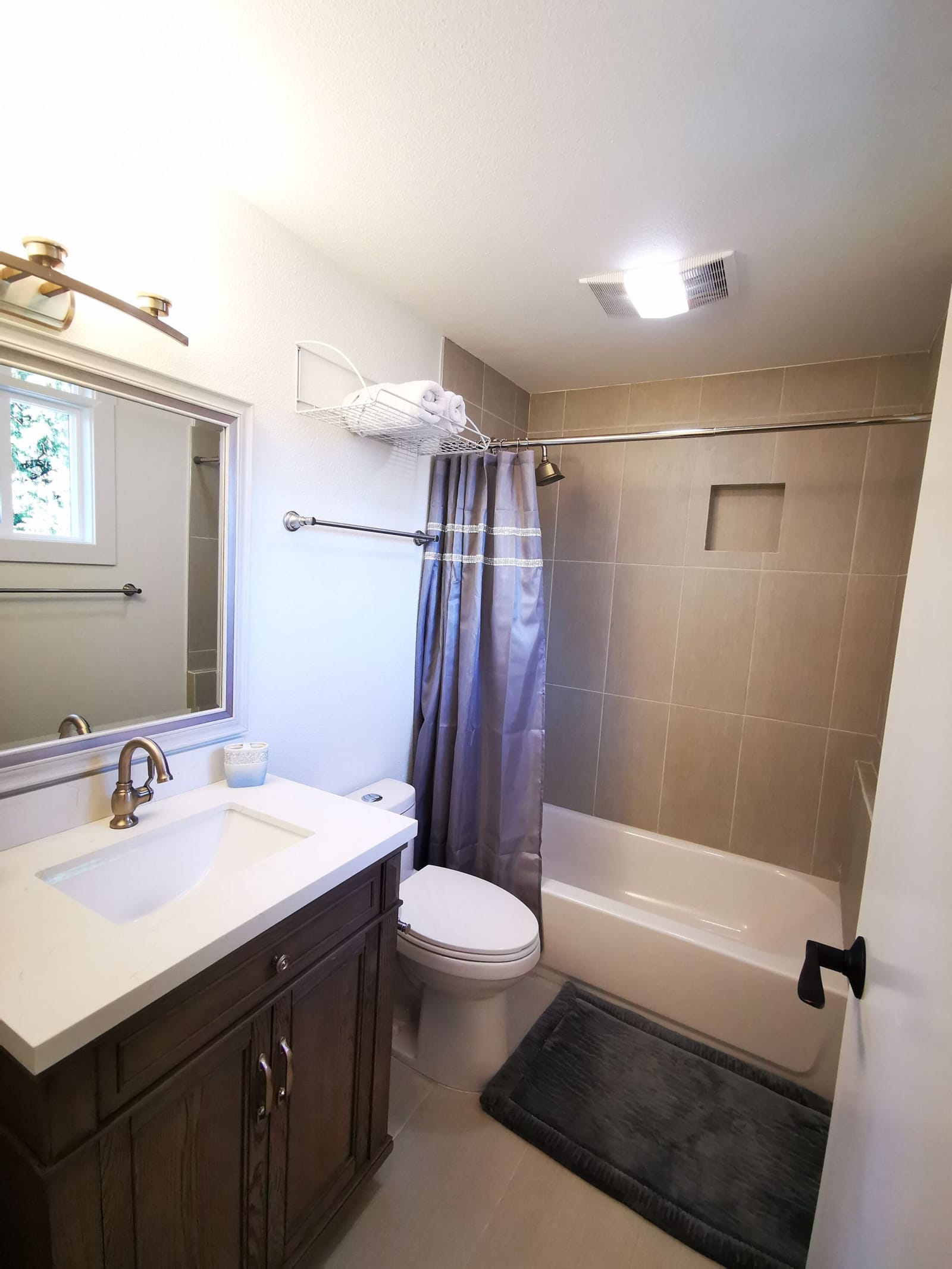 Bathroom with tub-shower, wood vanity and gray tiles
