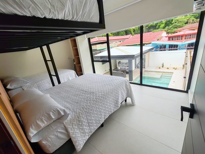 Upstairs bedroom with double bed under a bunk and pool view