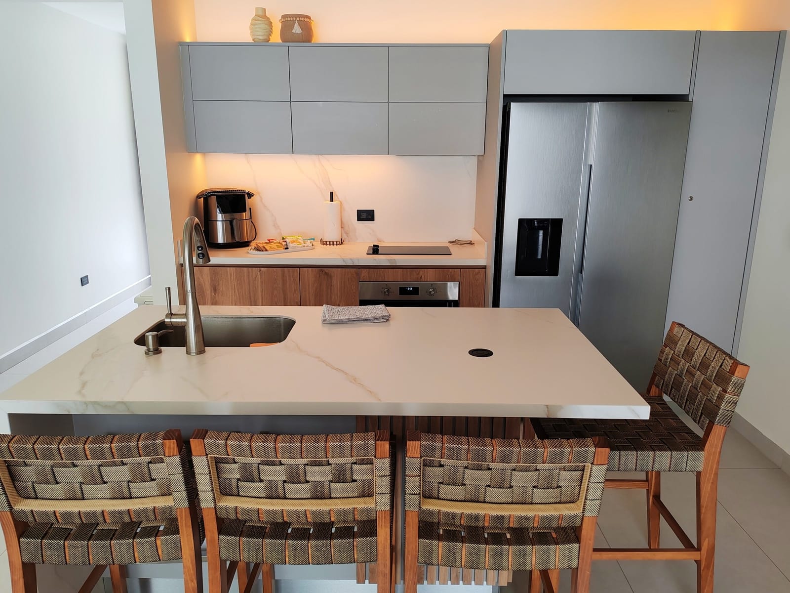 Kitchen island with woven bar stools and refrigerator