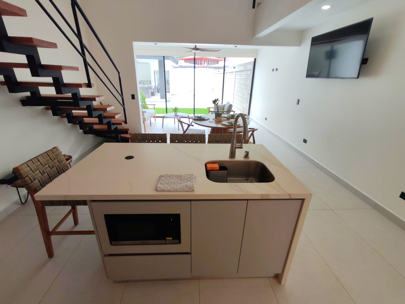 Floating wooden stair rising beside the white kitchen island