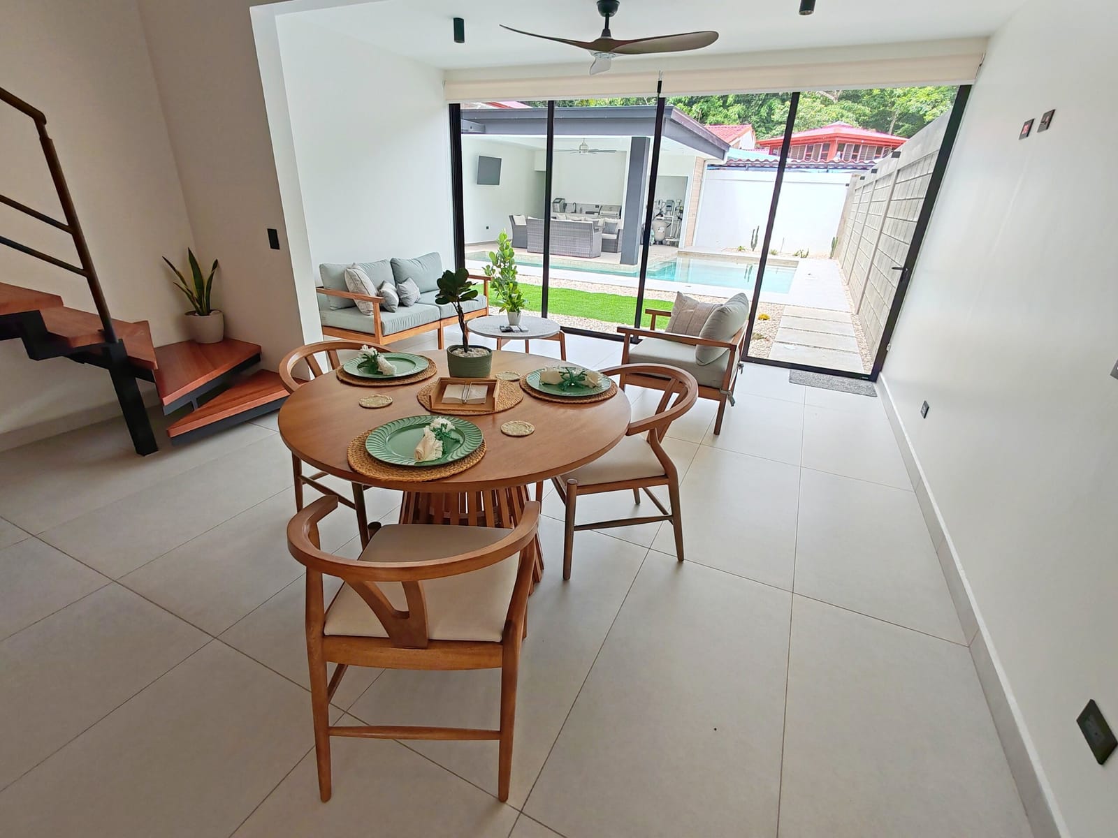 Round wooden dining table by the glass doors to the pool
