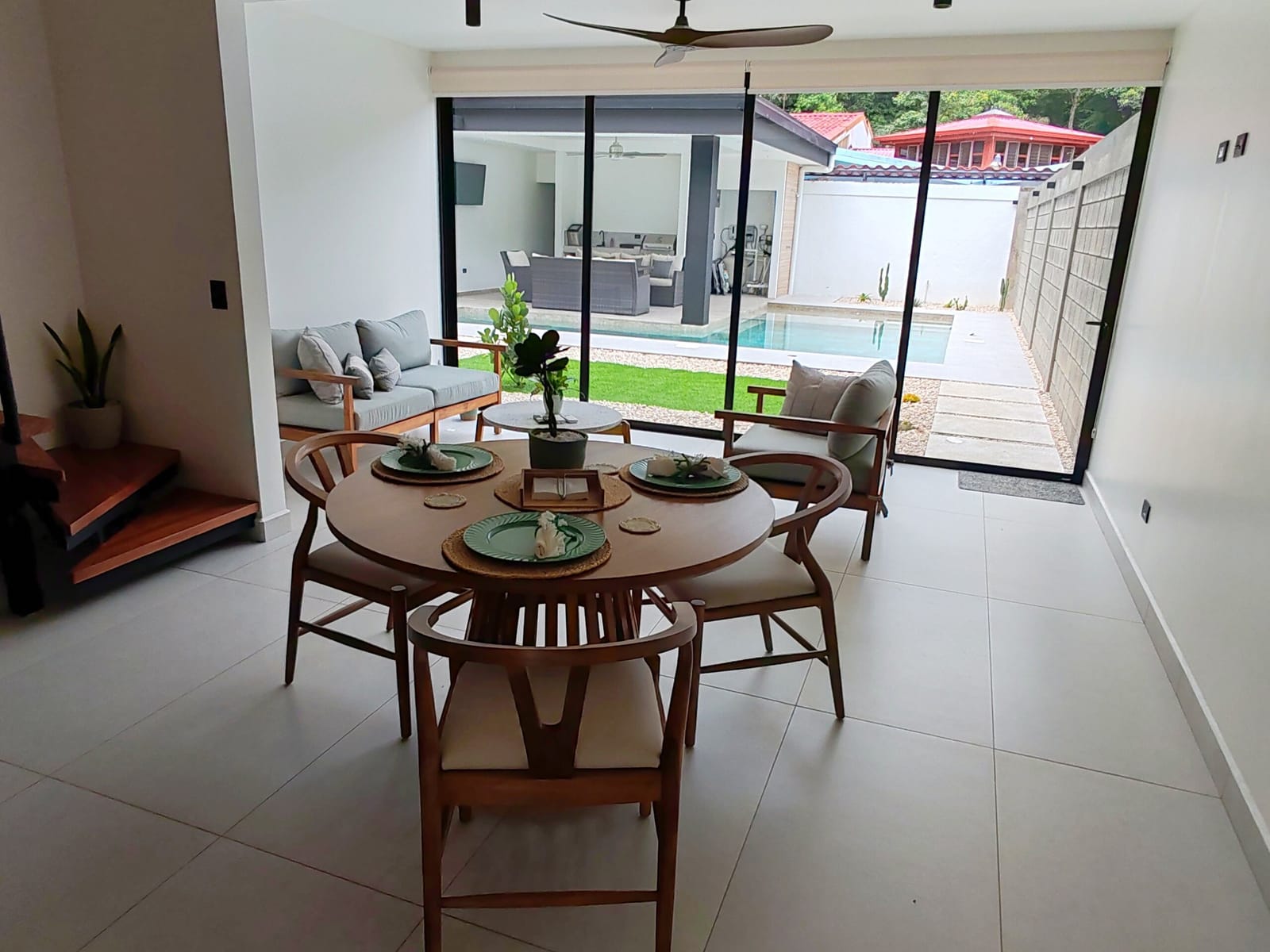 Dining table and sofa with the pool beyond the glass