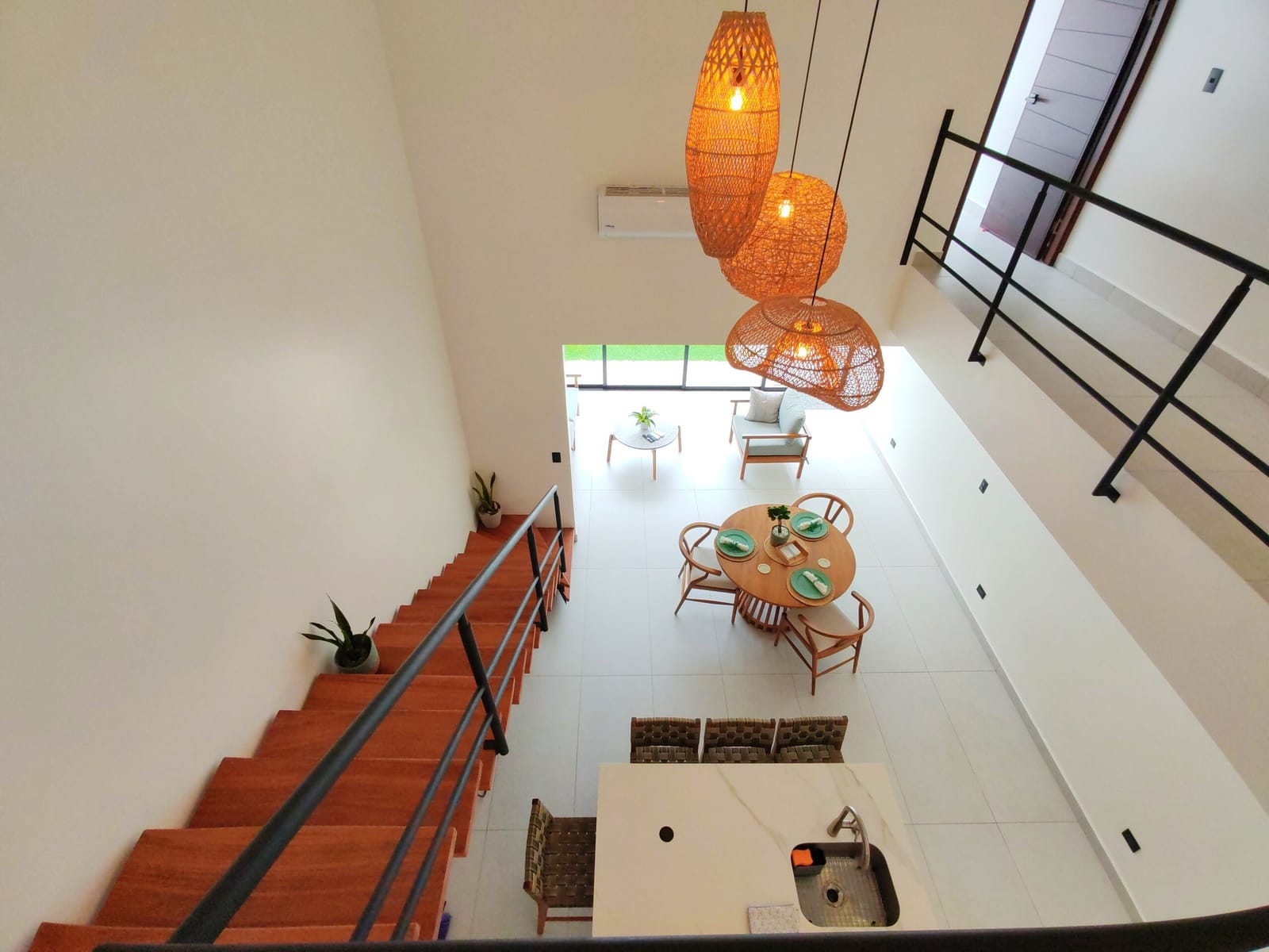 View down from the stair onto the dining table and rattan lamps