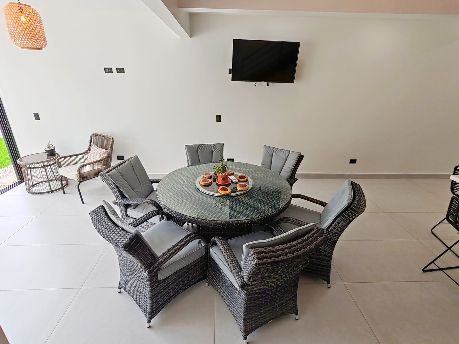 Round dining table with six rattan chairs and TV