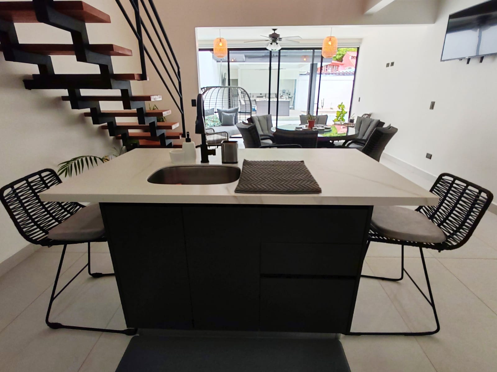 Kitchen island with black stools and the pool doors beyond