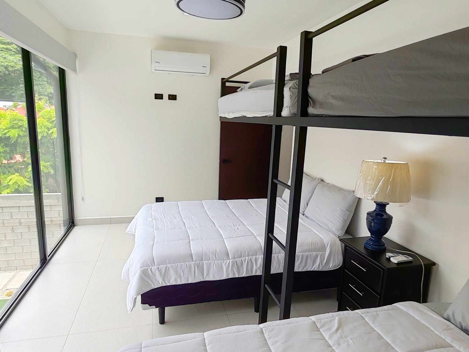 Bunk bed over a double bed with glass door and lamp